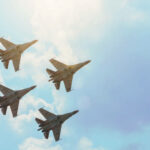 Group of four aircraft fighter jet airplane sun glow toned gradient clouds sky