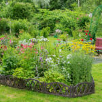 Summer garden area with flower beds and a wooden bench for relaxation.