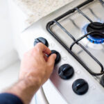 Hands of a man turning knob to light a gas stove